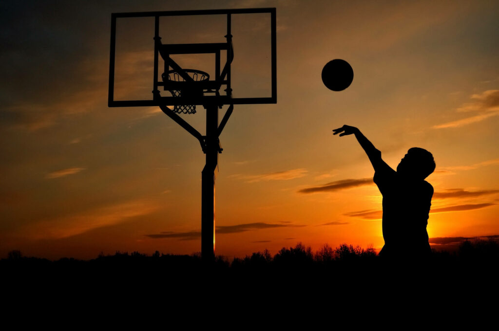 Silhouetted Basketball Player at Sunset – Serene Wallpaper Background