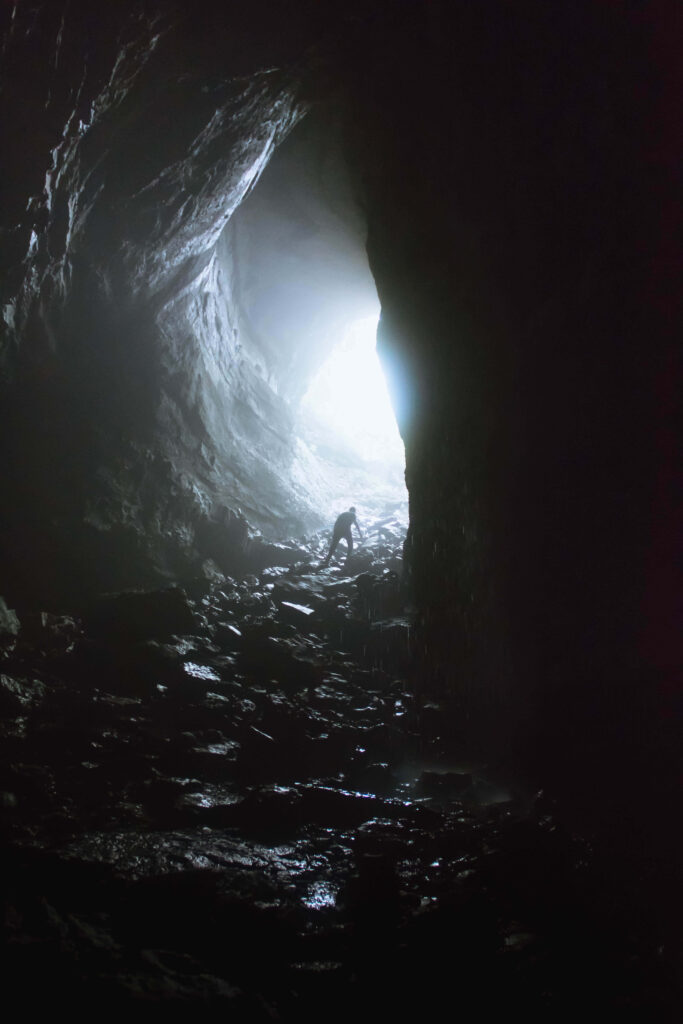 Silhouetted Figure at Cave Entrance: Light and Mystery Unveiled Wallpaper