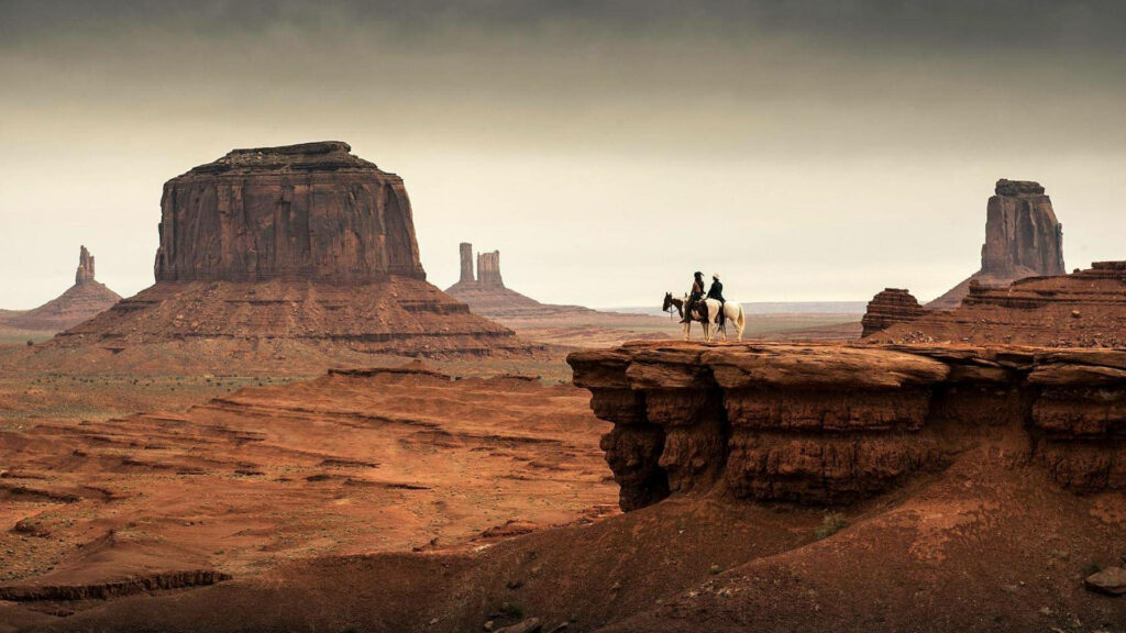Desert Riders: Majestic Cowboys Embrace Monument Valley Wallpaper