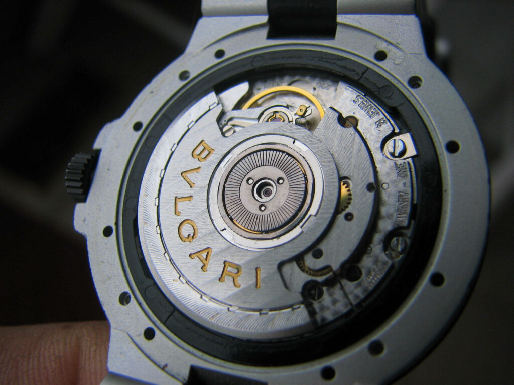 Close-up of silver Bvlgari watch gears showcasing intricate craftsmanship and gold branding details Wallpaper