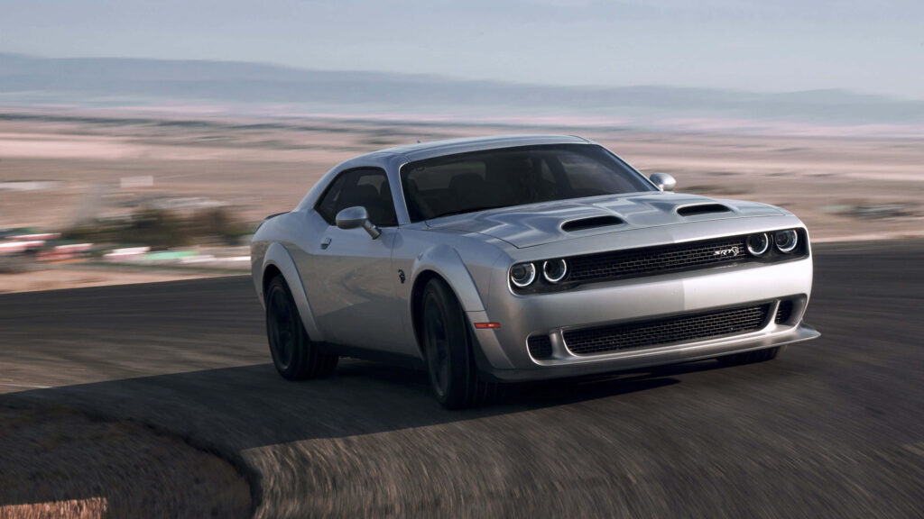 Silver Dodge Hellcat racing on curved track showcasing aggressive design and high performance Wallpaper