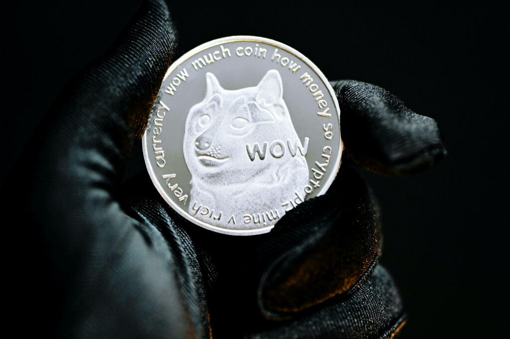Close-up of silver Dogecoin token with Shiba Inu meme on dark metallic cryptocurrency wallpaper
