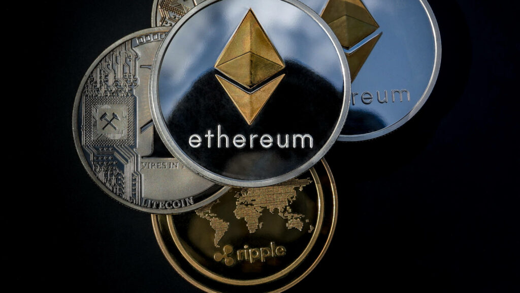 Close-up of silver Ethereum coins with gold logo Litecoin and Ripple crypto on dark background Wallpaper