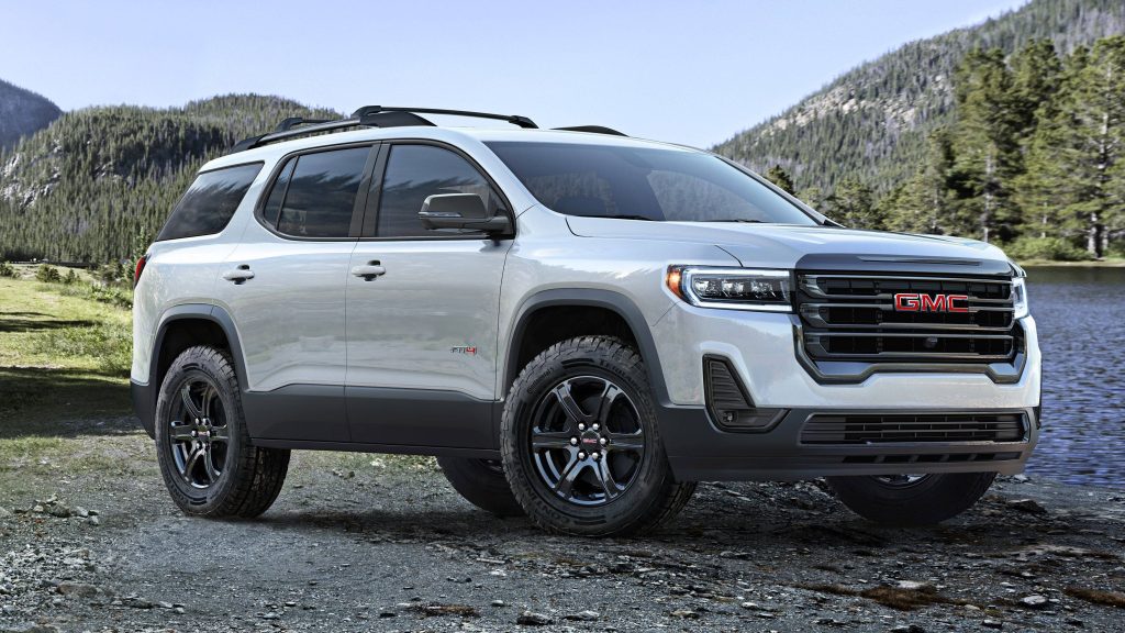 Silver GMC Acadia AT4 with black wheels parked by serene mountain lake off-road SUV wallpaper