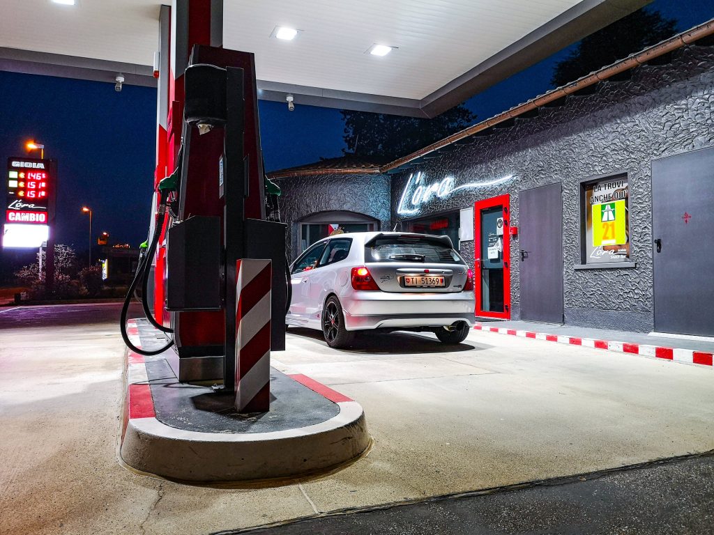 Silver Honda Civic Type R parked at modern red white gas station with neon Lora sign at night Wallpaper