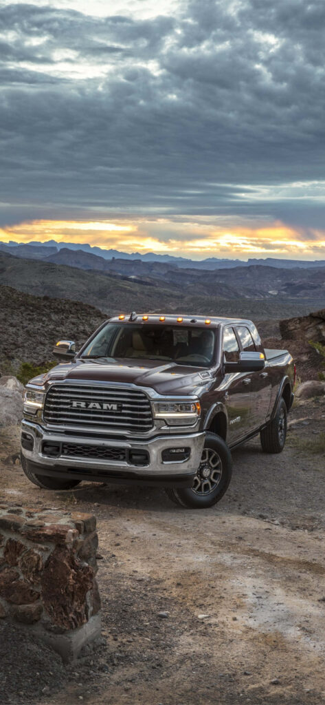 Silver RAM 2500 pickup on rugged terrain with sunset mountain landscape high-resolution photo Wallpaper