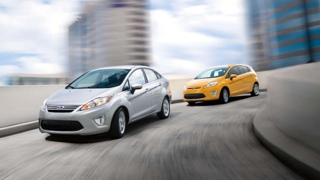 Silver and yellow Ford Fiesta cars racing on city road showcasing urban agility and speed Wallpaper