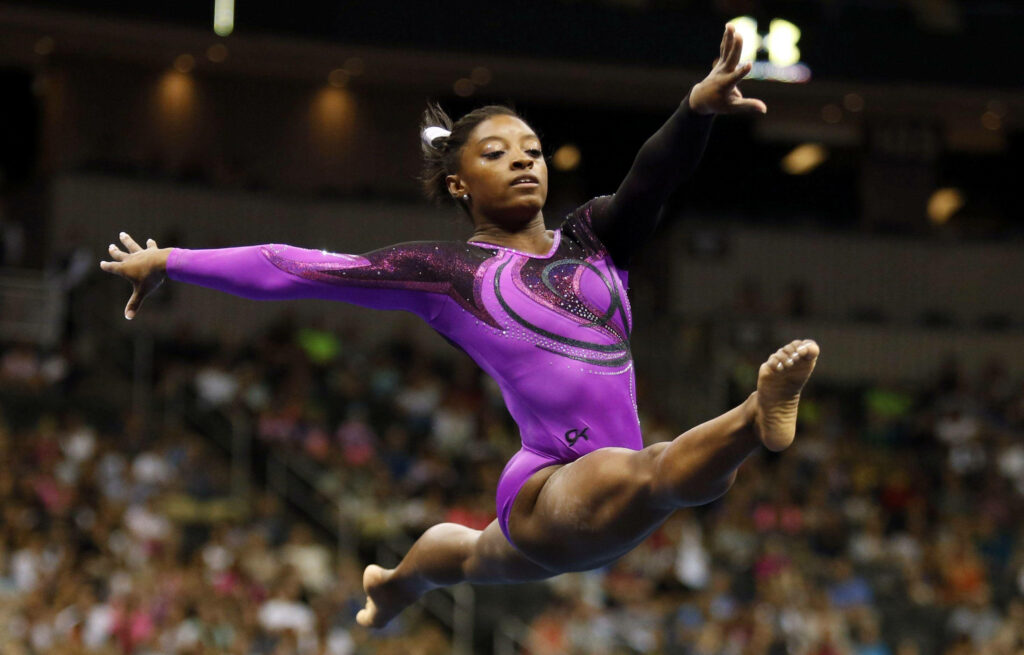 Simone Biles: Graceful Gymnastics Routine in Purple Leotard Wallpaper