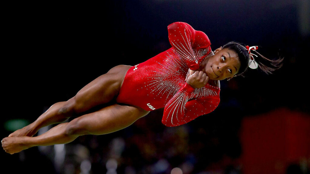 Simone Biles Mid-Air: Dynamic Gymnastics Wallpaper Background
