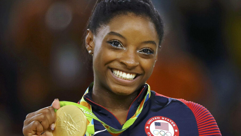 Simone Biles: Radiant Smile & Gold Medal Inspiring Wallpaper Background