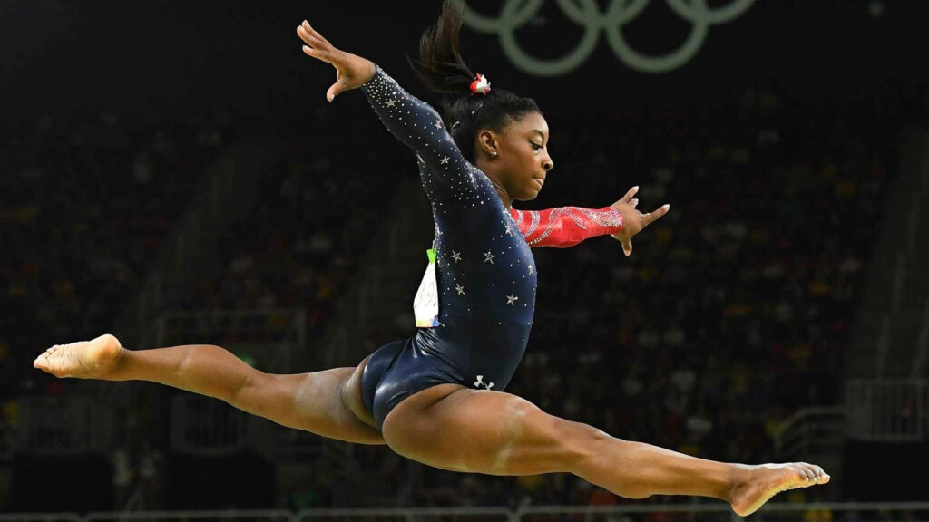 Stunning Simone Biles Leap: Gymnastics Wallpaper Background