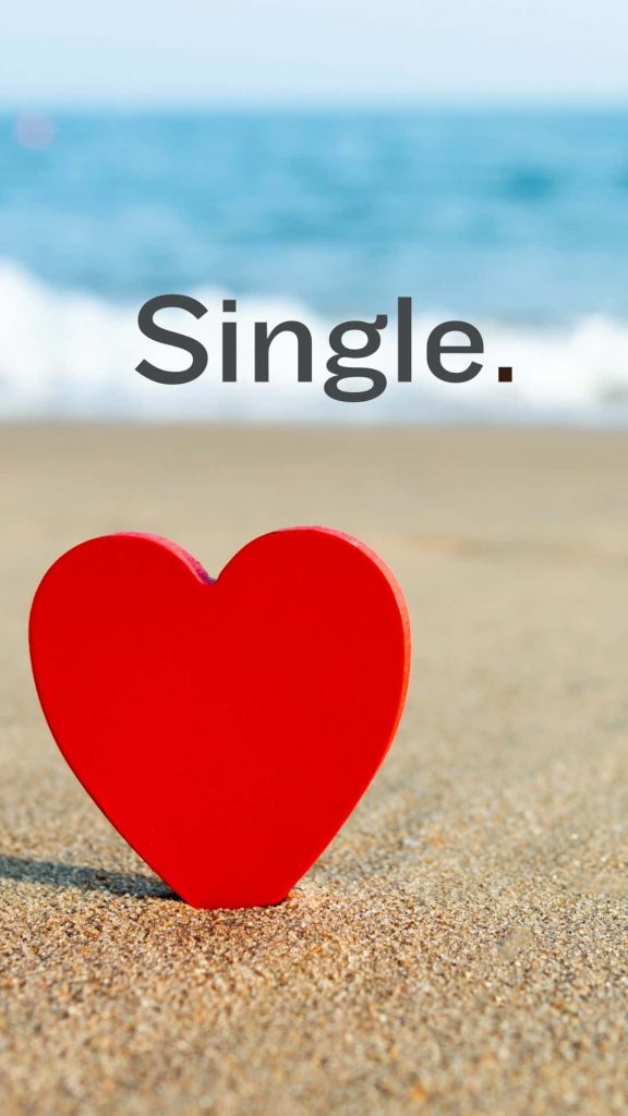 Vibrant red heart on sandy shore with single text ocean background romantic wallpaper