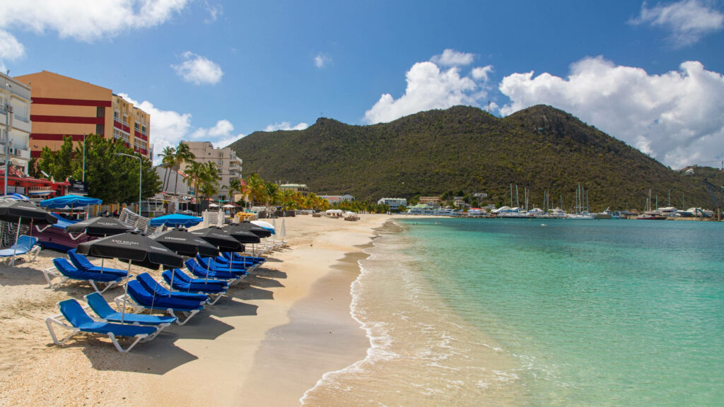 Tropical Beach Scene in Sint Maarten: Chairs, Umbrellas & Serenity Wallpaper