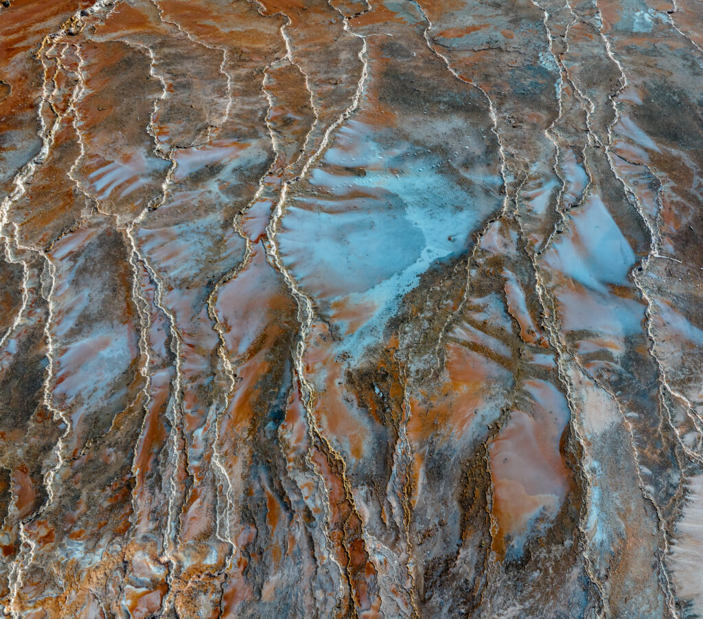 Sinter terraces wallpaper with layered mineral deposits in earthy brown rust and pale blue tones