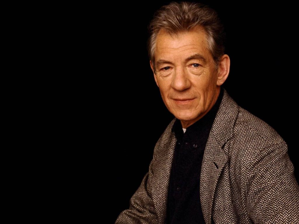 Sir Ian McKellen portrait in herringbone tweed jacket serene expression black background wallpaper