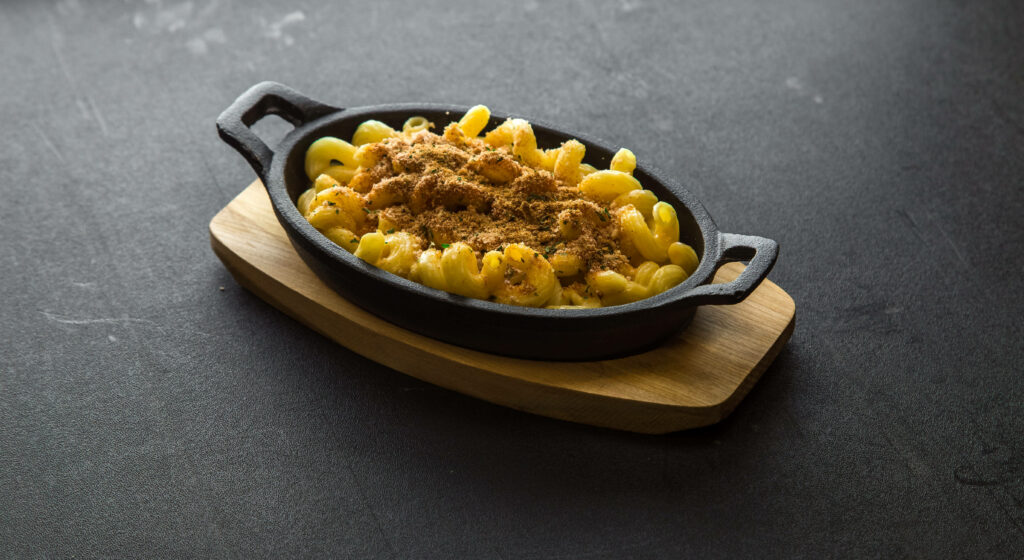 Sizzling Creamy Mac and Cheese with Garnish on Wooden Base Wallpaper