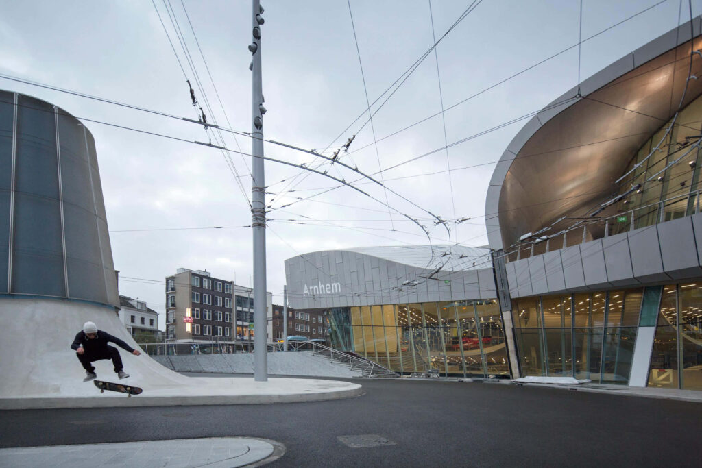Skateboarder performing urban trick by modern architecture in Arnhem cityscape wallpaper background