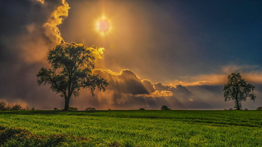 Resilient Beauty: Majestic Clouds and Golden Sunlight Illuminate Serene Countryside Wallpaper