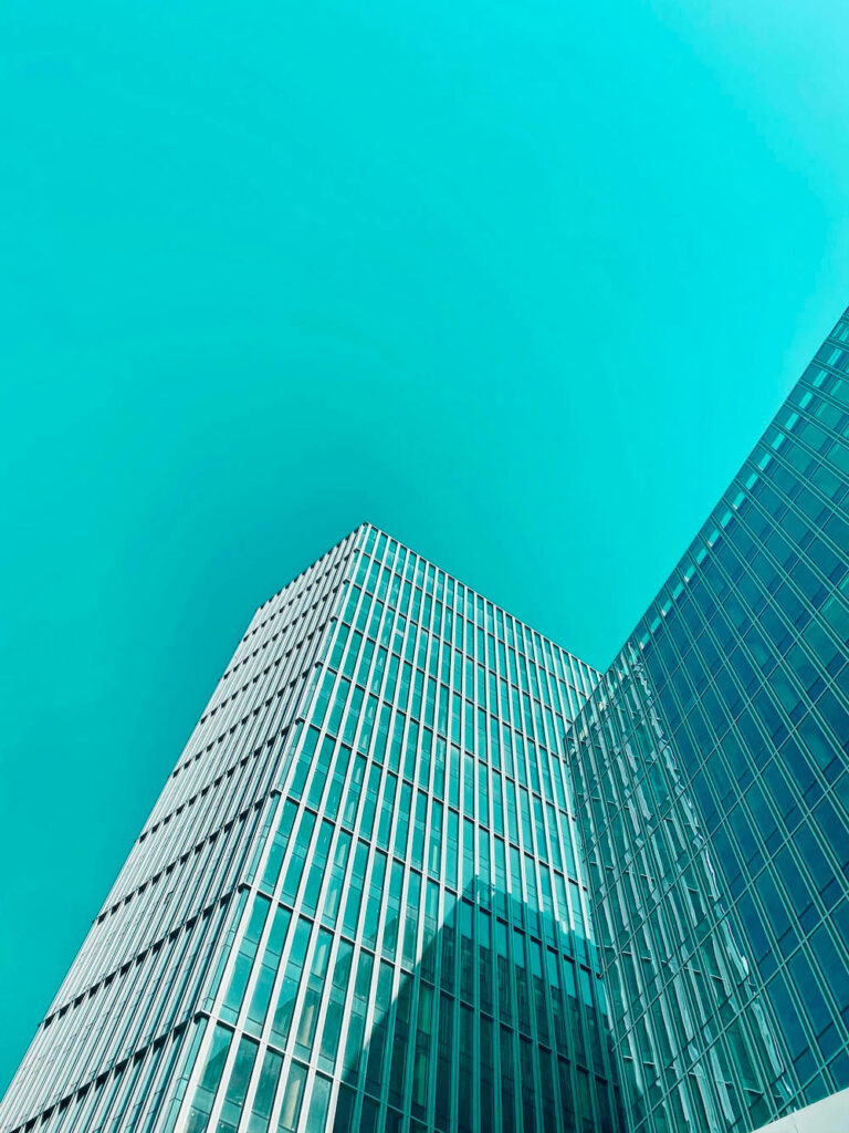 Reaching the Sky: Capturing the Majestic Height of a Tall Building against a Striking Cyan Background Wallpaper