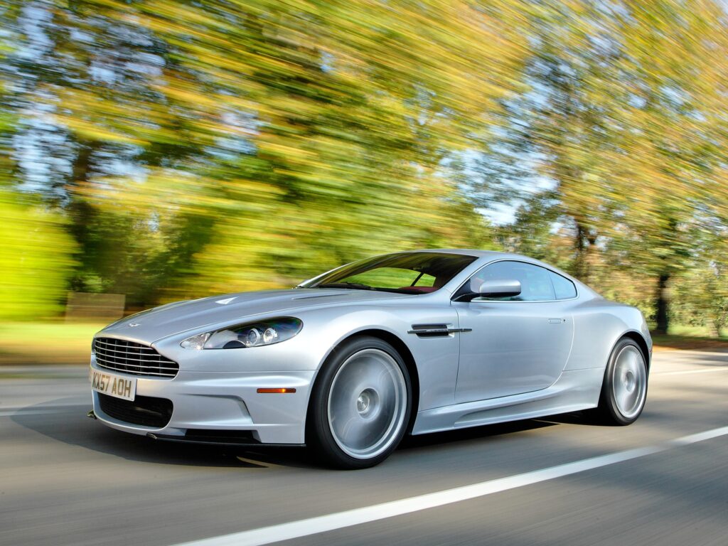2008 Aston Martin DBS: Sleek Silver Wallpaper with Dynamic Background