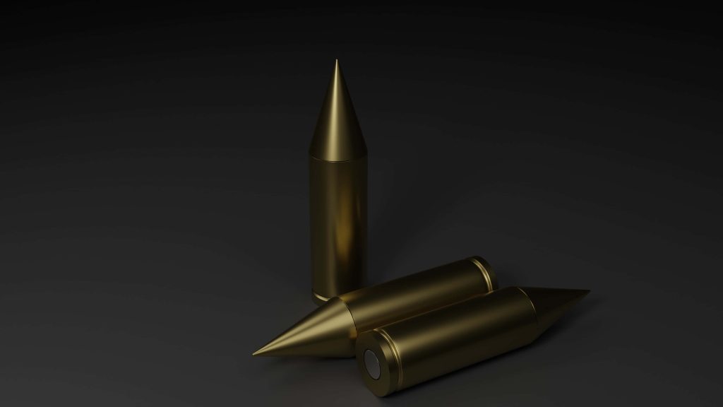 Three polished golden bullets on dark minimalist background with soft focused lighting wallpaper