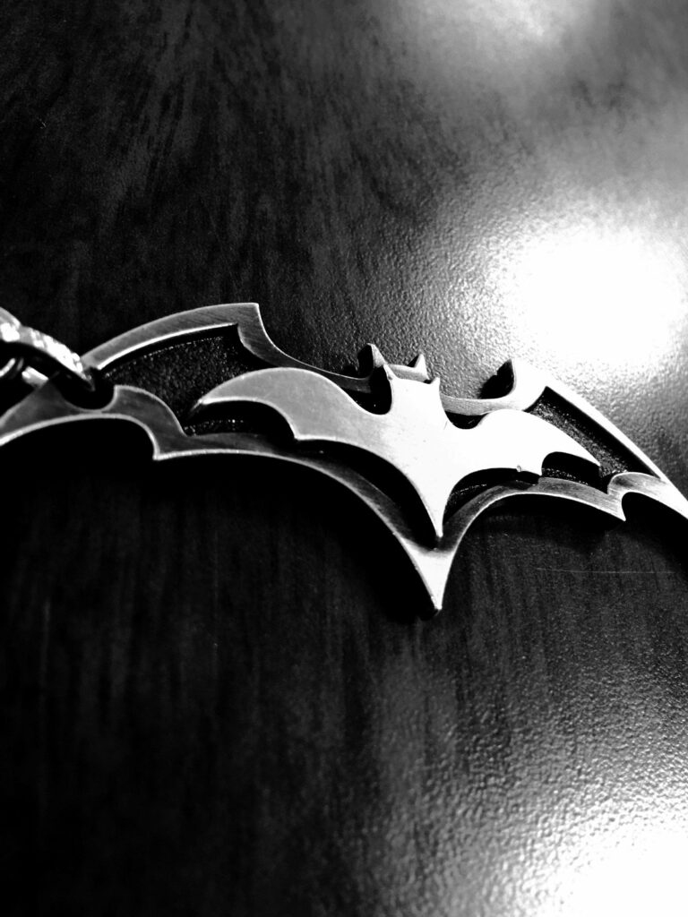 3D metal Batman logo on dark reflective background sleek bold iPhone wallpaper for superhero fans