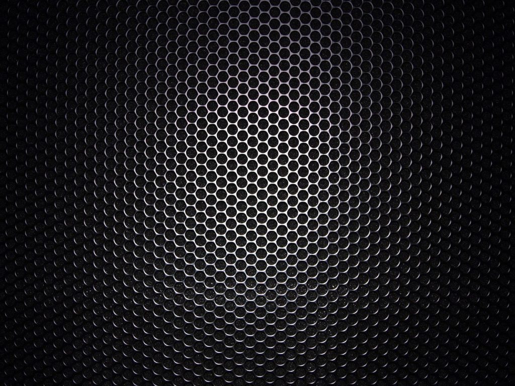 Abstract perforated metal mesh wallpaper with spotlight and dark edges for tech minimalist desktop