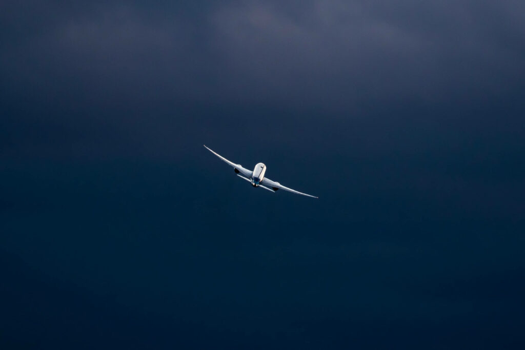 Sleek Airplane Soaring Through Dramatic Overcast Sky - Aviation Essence Wallpaper