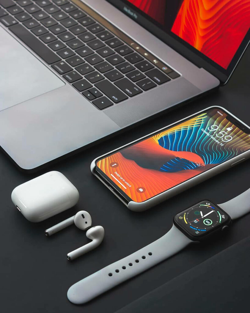 Vibrant Apple Gadgets Wallpaper: MacBook, iPhone & More on Dark Surface