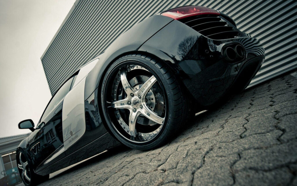 Audi R8 low angle shot with glossy black tires and industrial background wallpaper design
