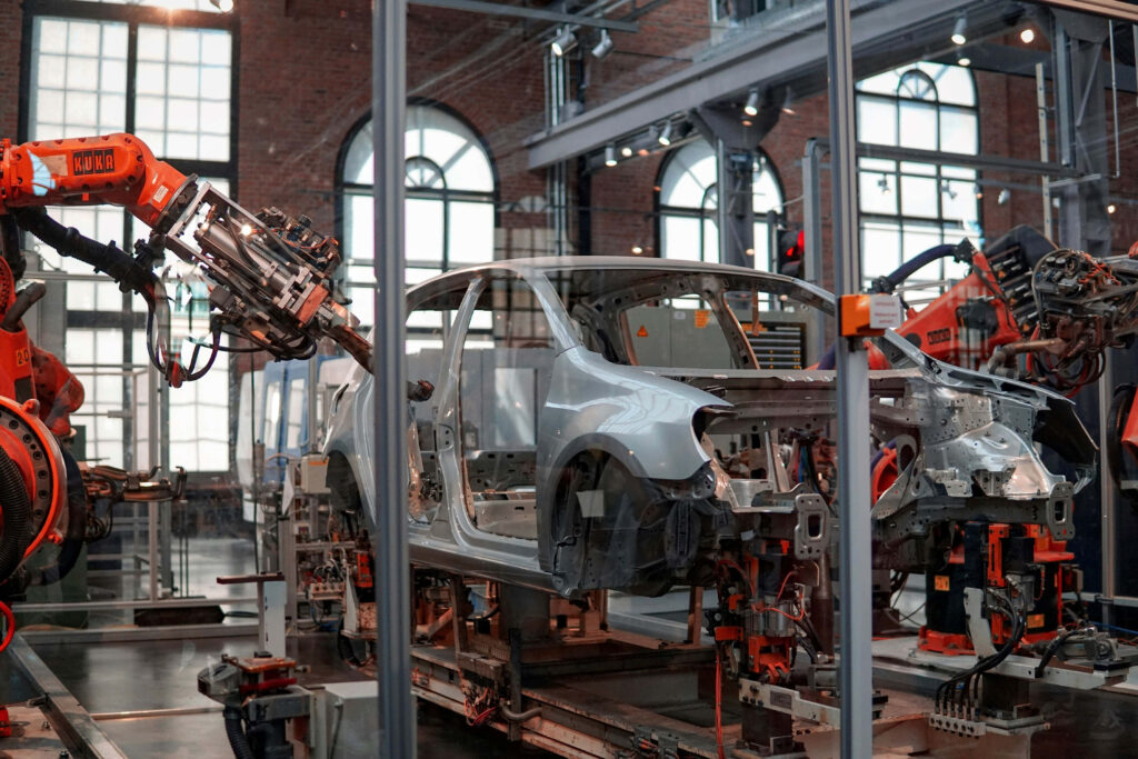 Industrial robotic arms assembling a metallic car frame in a bright modern factory wallpaper background