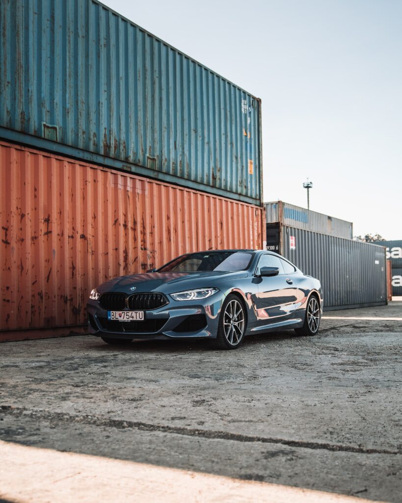 Sleek BMW Car Front View Against Colorful Shipping Containers Background Wallpaper