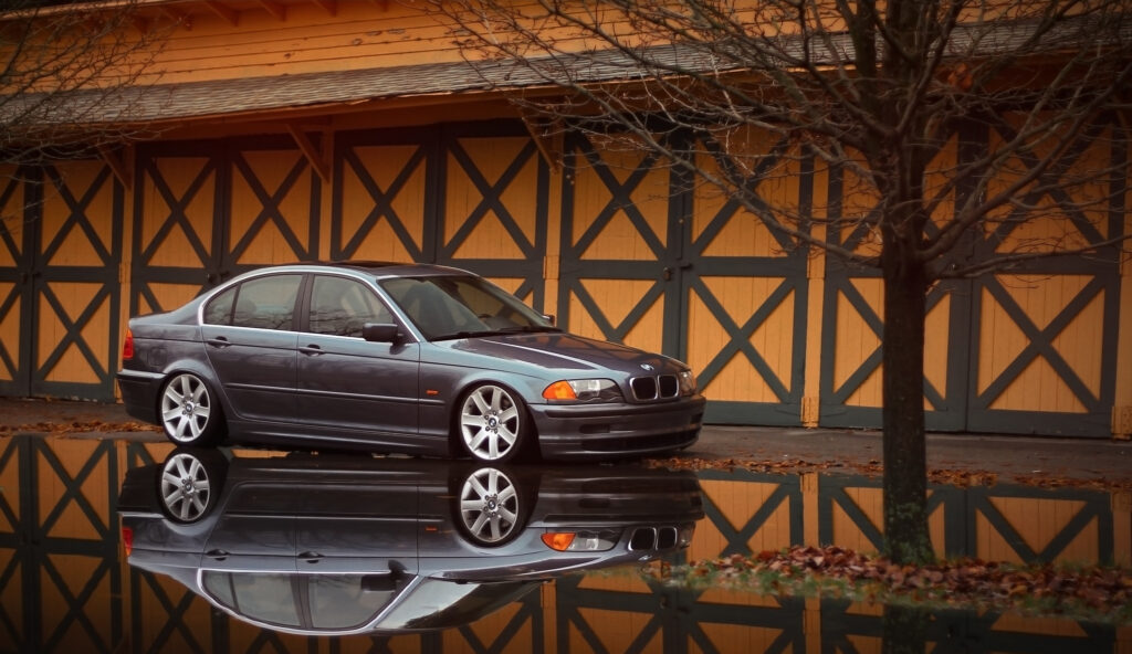 Sleek BMW E46 Side View Wallpaper with Rustic Background Reflection