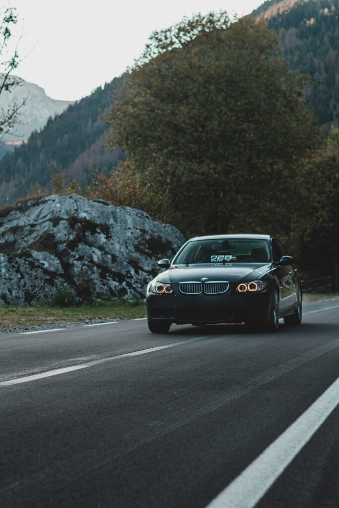 Sleek BMW Front View on Scenic Road with Lush Greenery Wallpaper