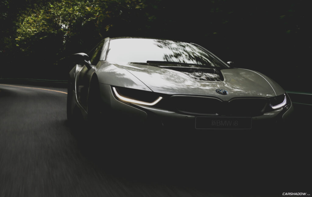 Sleek BMW i8 in Motion: Futuristic Design on a Forested Road Wallpaper