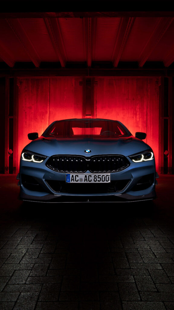 Sleek BMW illuminated by red glow in dim space showcasing modern design and powerful presence Wallpaper