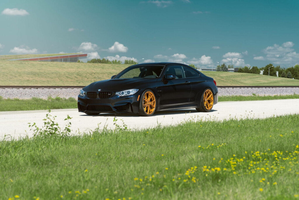 Golden-Accented Power: The Unstoppable BMW M4 Roaming on Sunlit Roads Wallpaper