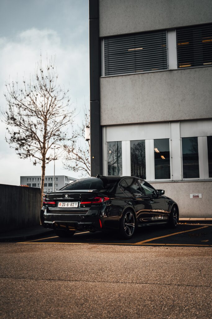 Glossy Black BMW: Urban Wallpaper with Modern Architecture Background