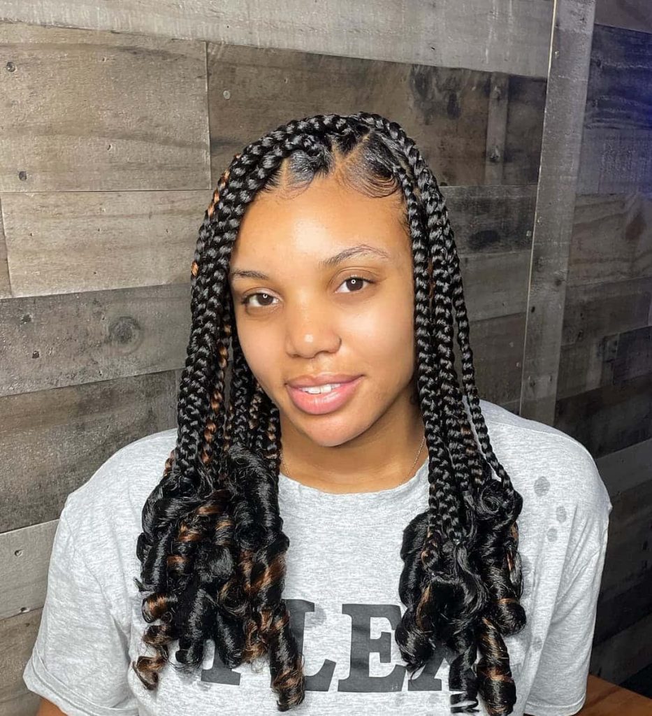 Portrait of woman with sleek black box braids and copper highlights against rustic wood backdrop Wallpaper