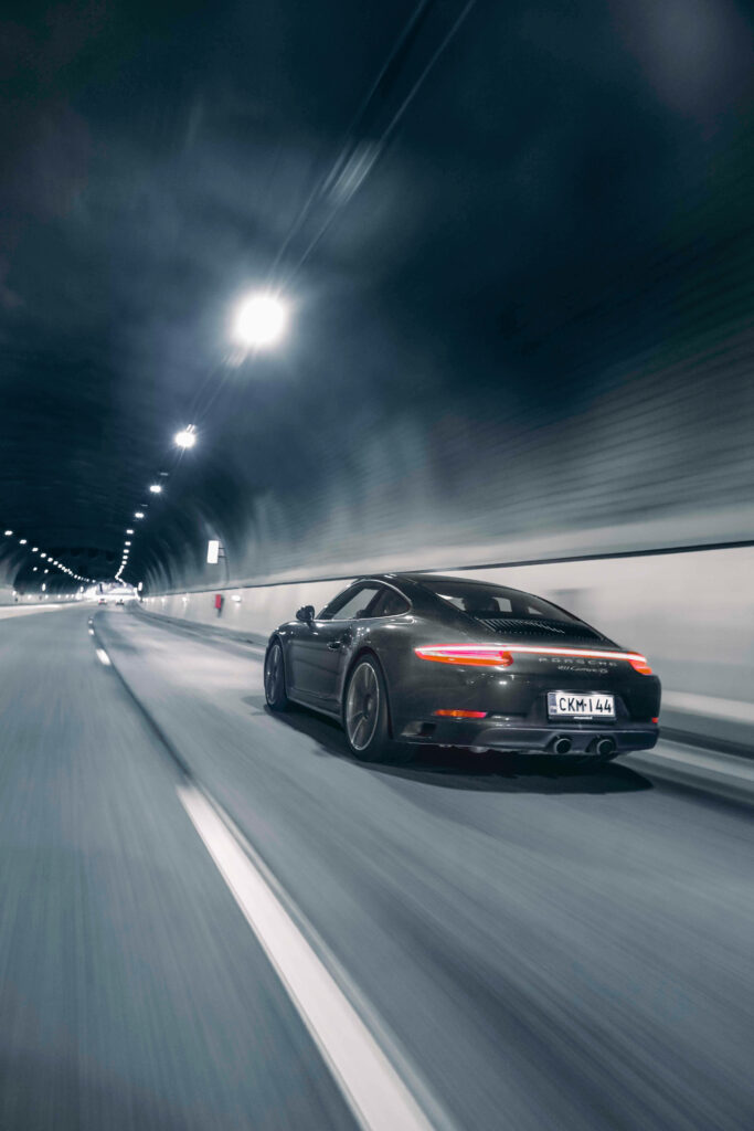Black sports car speeding through illuminated modern tunnel dynamic motion wallpaper background