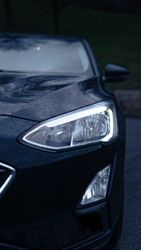 Dramatic Front View: Sleek Black Car with Glistening Headlights Wallpaper
