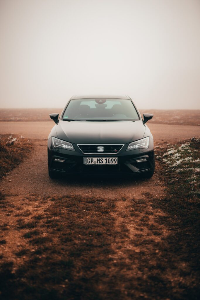 Sleek Black Car Wallpaper: Front View on Rugged Path with Mist
