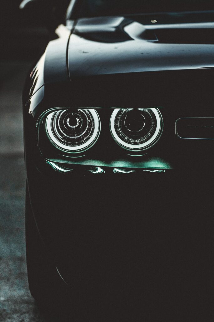 Striking Black Car in Dark Setting with Vibrant Headlights Wallpaper