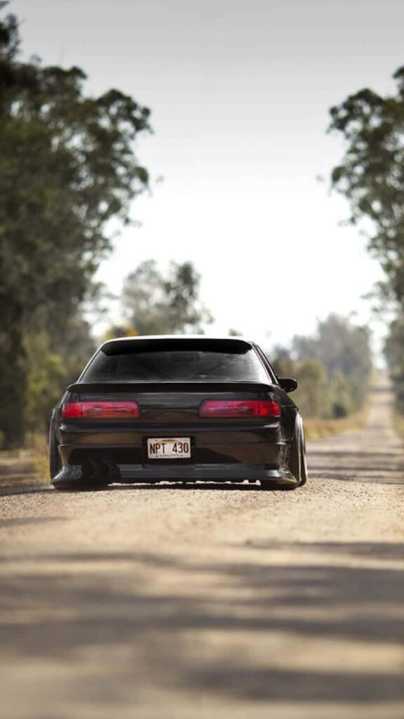 Sleek black car parked on sunlit tree-lined rural road stylish serene iPhone wallpaper background