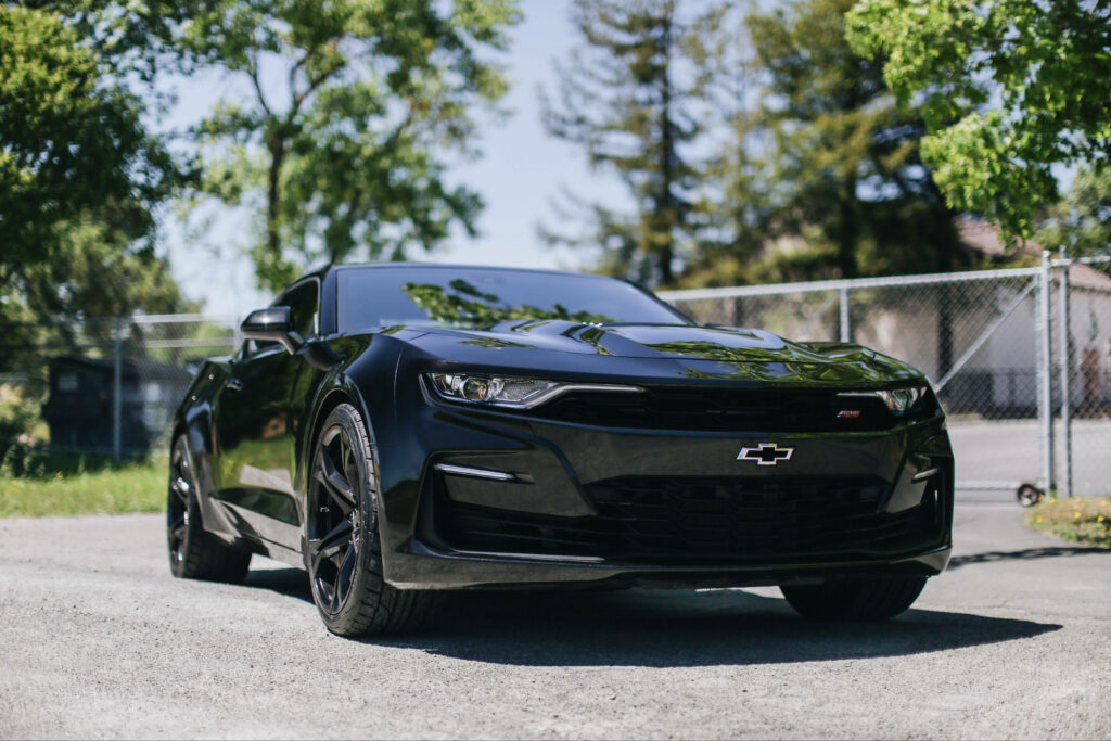 Sleek Black Chevrolet Supercar Wallpaper with Lush Greenery