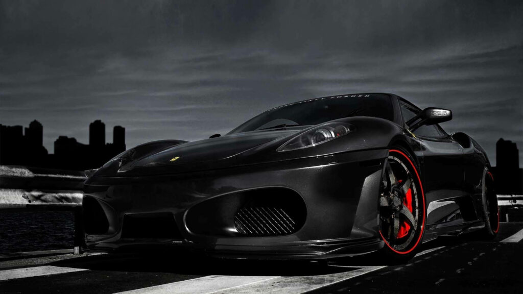 Sleek black Ferrari F430 with red rims against moody cityscape HD wallpaper background