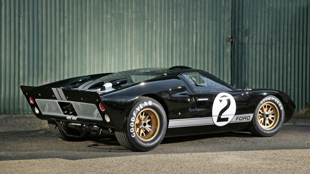 Black Ford GT sports car with gold wheels and racing decals rear view on metal wall background Wallpaper