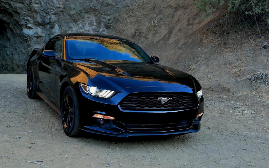 Front View Black Ford Mustang in Rugged Landscape Wallpaper