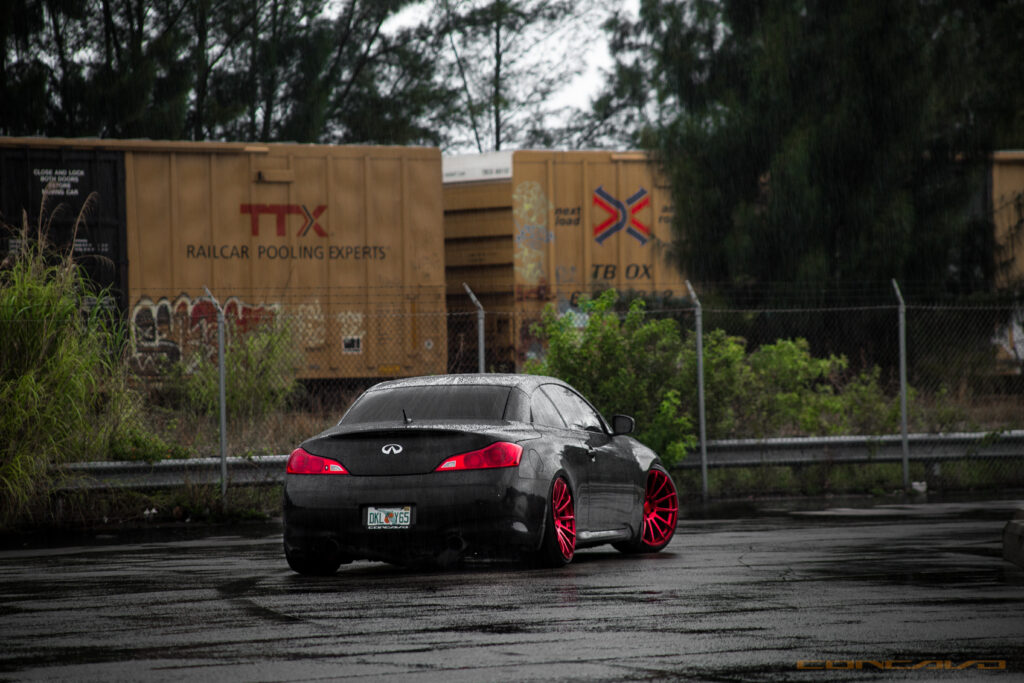 Edgy Black Infiniti Car Wallpaper with Red Rims Against Industrial Background