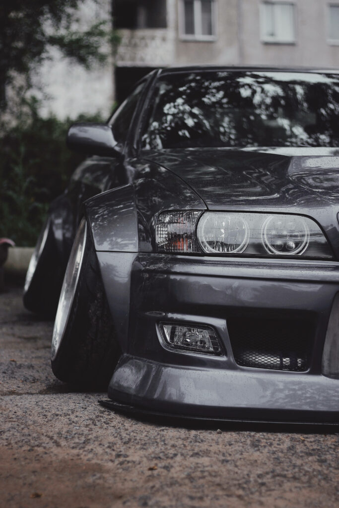 Sleek black JDM car with wide body kit lowered stance polished rims parked on concrete urban background Wallpaper